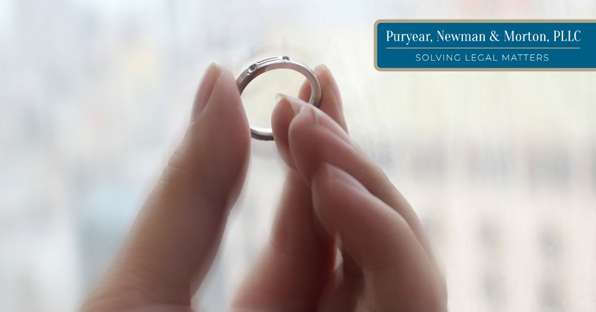 Woman holding a wedding ring between her fingers